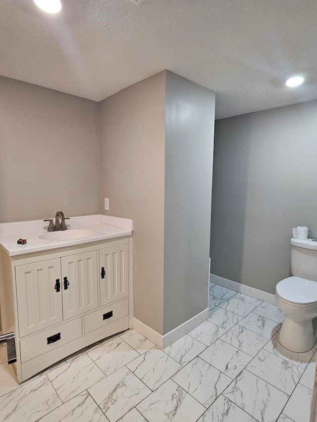 bathroom with vanity, toilet, and a textured ceiling