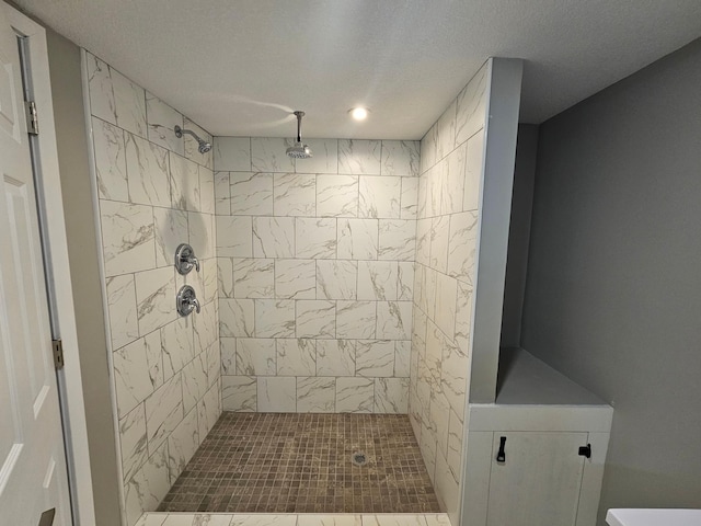 bathroom with a tile shower and a textured ceiling