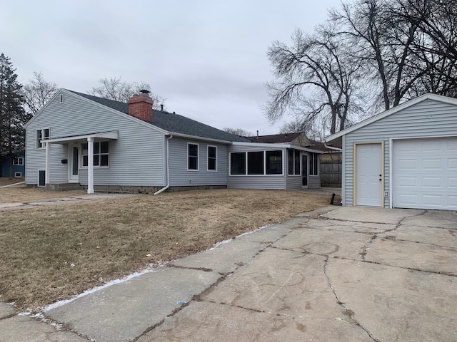 ranch-style home with an outdoor structure, a garage, a front yard, and a sunroom