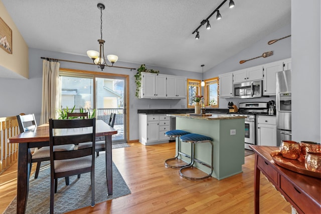 kitchen featuring a kitchen island, pendant lighting, white cabinetry, lofted ceiling, and stainless steel appliances