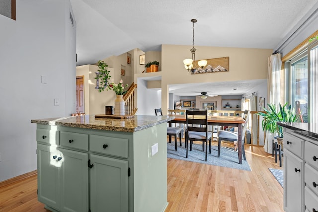 kitchen featuring lofted ceiling, a center island, hanging light fixtures, green cabinets, and light hardwood / wood-style floors