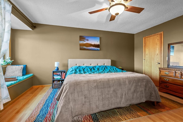 bedroom featuring hardwood / wood-style flooring, a textured ceiling, and ceiling fan