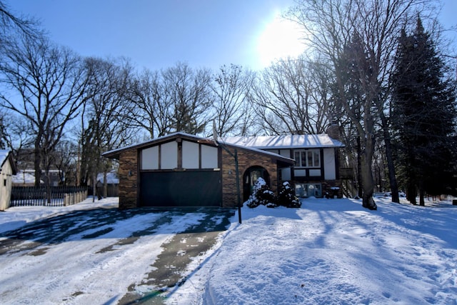 view of front of home featuring brick siding, a chimney, an attached garage, fence, and driveway