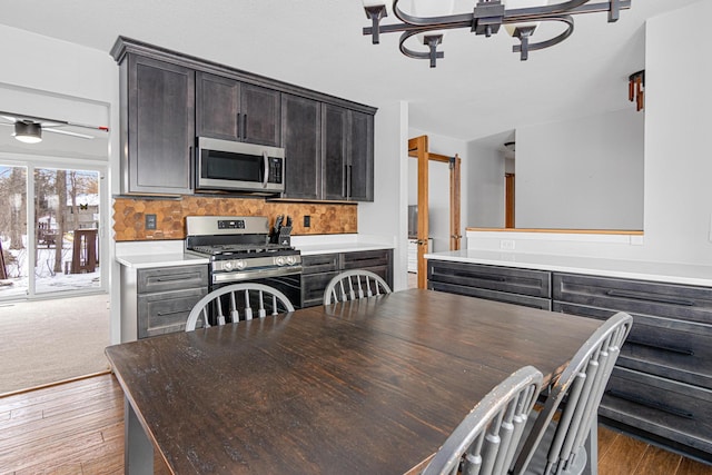 kitchen featuring decorative backsplash, dark wood-type flooring, dark brown cabinets, and appliances with stainless steel finishes