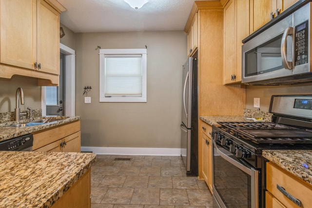 kitchen featuring light stone counters, stainless steel appliances, sink, and light brown cabinets