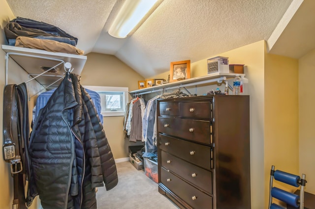 walk in closet with vaulted ceiling and light carpet