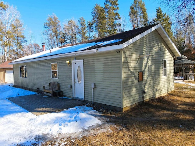 snow covered rear of property featuring a garage