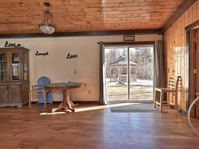 unfurnished dining area with baseboards, lofted ceiling, wood ceiling, and wood finished floors