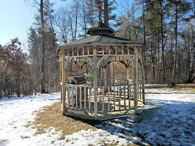 snow covered deck with a gazebo, grilling area, and a forest view