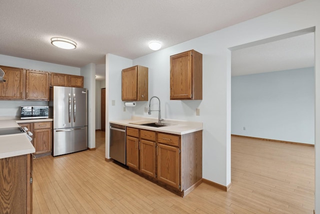 kitchen with sink, a textured ceiling, light hardwood / wood-style flooring, and stainless steel appliances