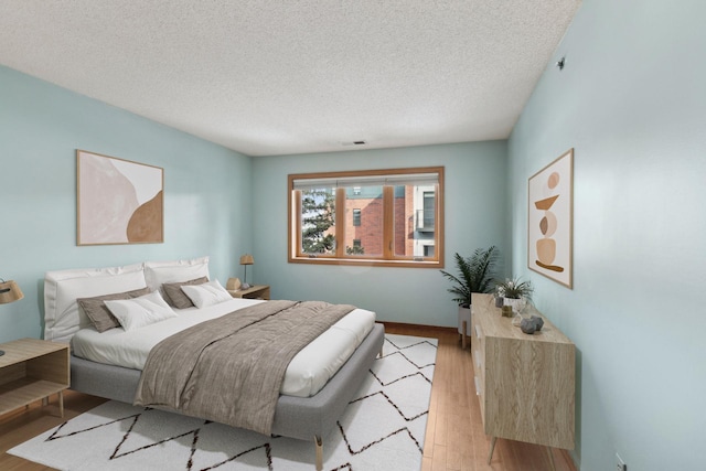 bedroom featuring light hardwood / wood-style floors and a textured ceiling