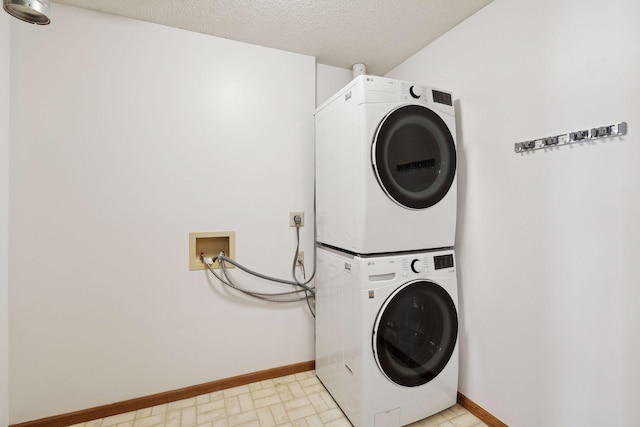 washroom with a textured ceiling and stacked washing maching and dryer