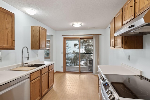 kitchen featuring a sink, brown cabinetry, stainless steel appliances, under cabinet range hood, and visible vents