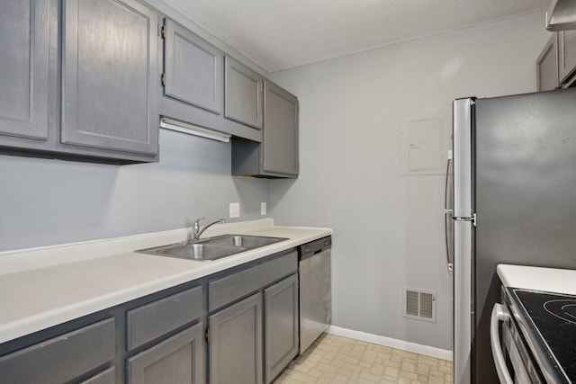 kitchen featuring a textured ceiling, stainless steel appliances, gray cabinetry, and sink