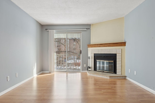 unfurnished living room with a textured ceiling, light hardwood / wood-style flooring, and a fireplace