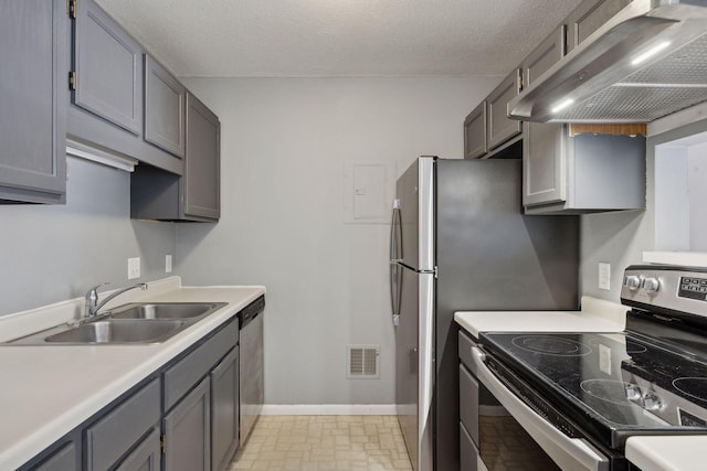 kitchen featuring appliances with stainless steel finishes, gray cabinetry, a textured ceiling, range hood, and sink