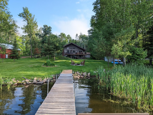 view of dock featuring an outdoor fire pit, a lawn, and a water view