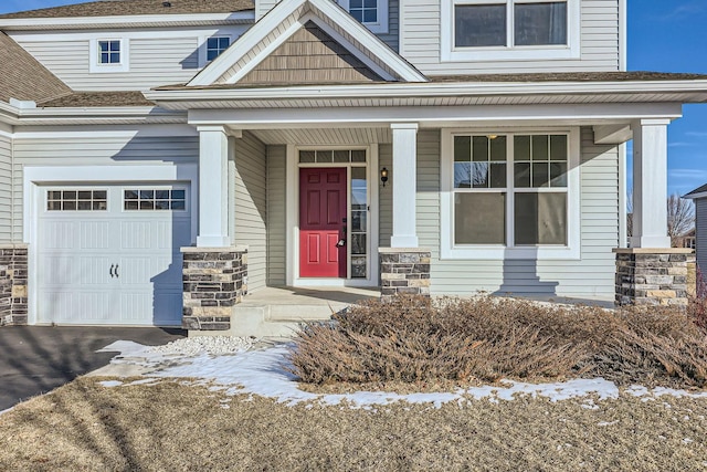 view of exterior entry with a garage and covered porch