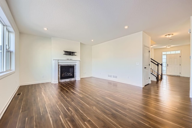 unfurnished living room with dark hardwood / wood-style flooring, a tile fireplace, and a textured ceiling