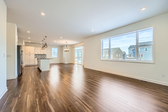 unfurnished living room with dark wood-type flooring and a chandelier