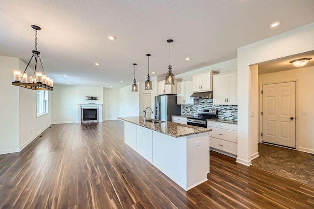 kitchen with white cabinetry, sink, dark stone counters, a kitchen island with sink, and stainless steel appliances