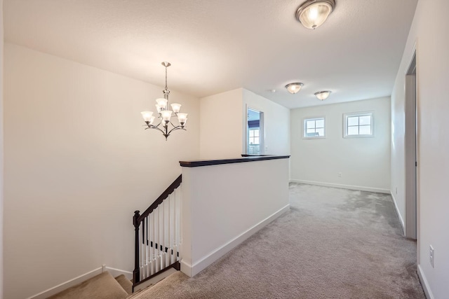 hall with an inviting chandelier and carpet floors