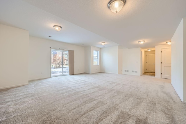 spare room with light carpet and a textured ceiling