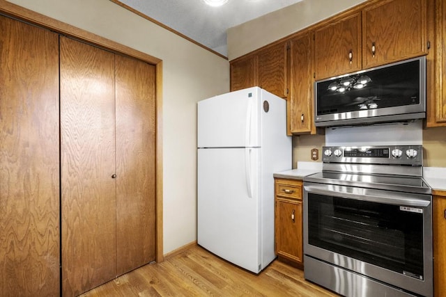 kitchen featuring crown molding, appliances with stainless steel finishes, and light hardwood / wood-style floors