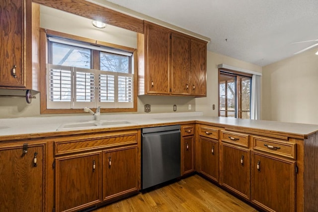 kitchen with dishwasher, sink, light wood-type flooring, and kitchen peninsula