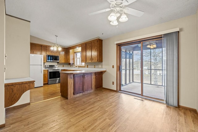 kitchen with appliances with stainless steel finishes, decorative light fixtures, light wood-type flooring, and kitchen peninsula