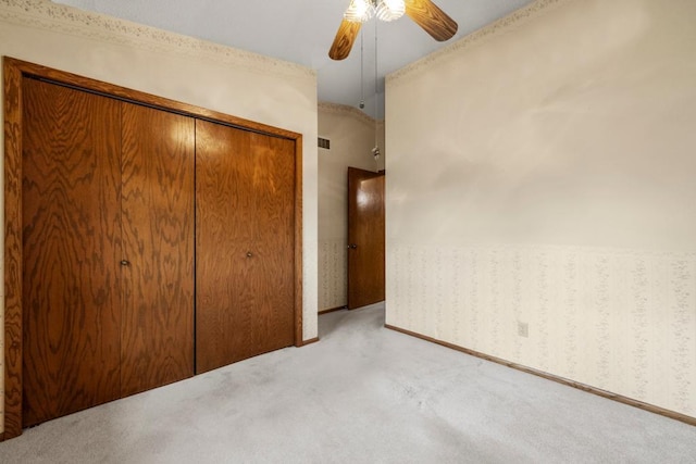 unfurnished bedroom with ceiling fan, light colored carpet, and a closet