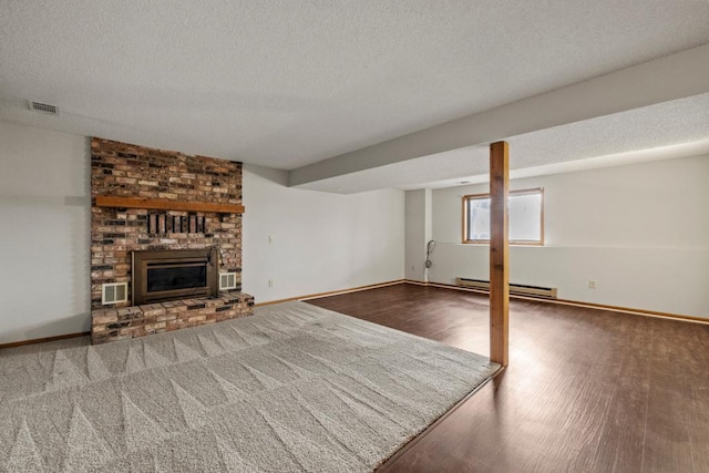 unfurnished living room with wood-type flooring, a textured ceiling, a fireplace, and a baseboard radiator