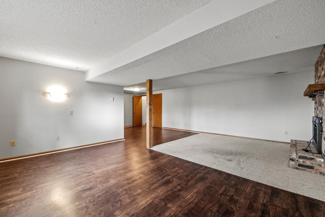 basement featuring a fireplace, dark wood-type flooring, and a textured ceiling