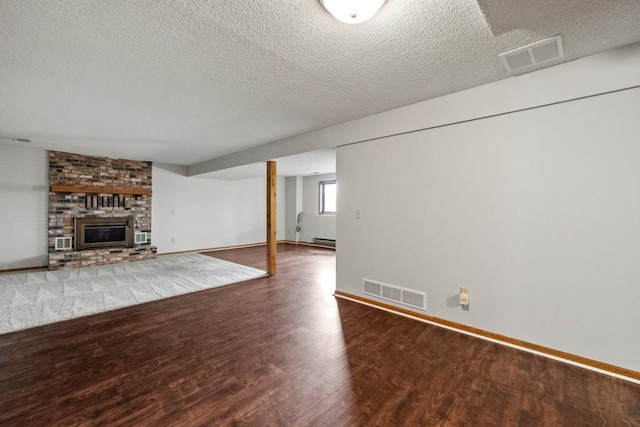 basement with wood-type flooring, a brick fireplace, and a textured ceiling