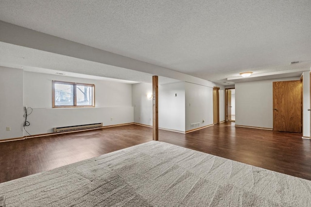 basement with dark wood-type flooring, a baseboard radiator, and a textured ceiling