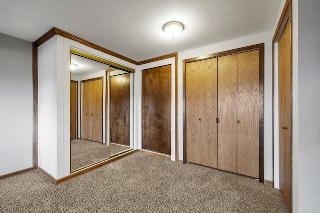 unfurnished bedroom featuring multiple closets and carpet flooring