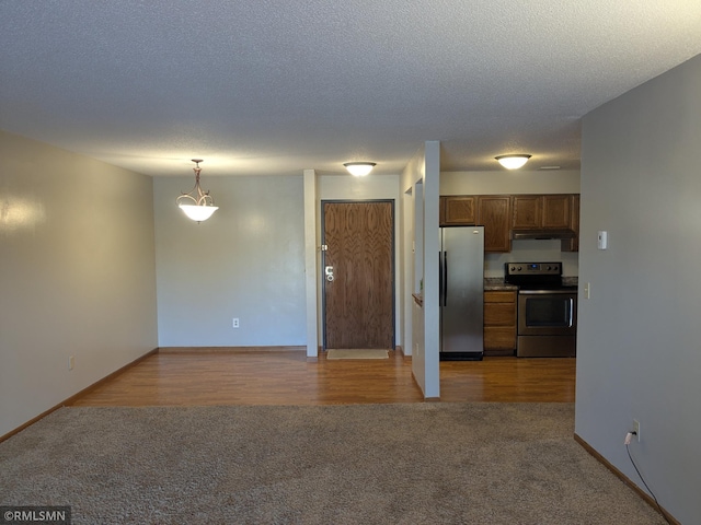 kitchen featuring decorative light fixtures, light colored carpet, a textured ceiling, and appliances with stainless steel finishes