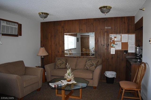 carpeted living room featuring a wall mounted air conditioner, wood walls, sink, and a textured ceiling