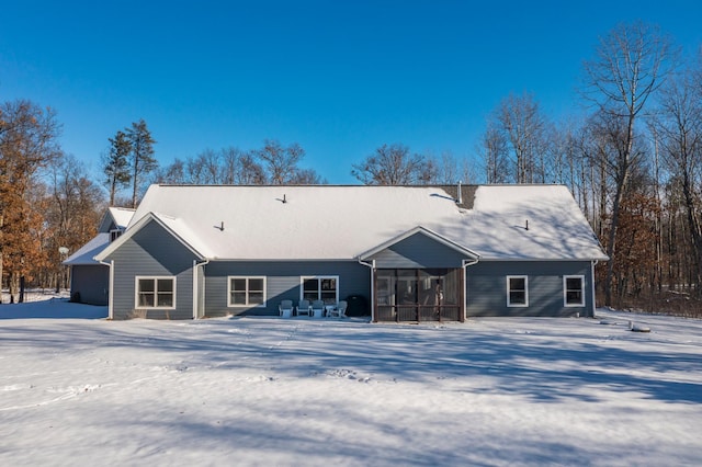 snow covered back of property with a sunroom