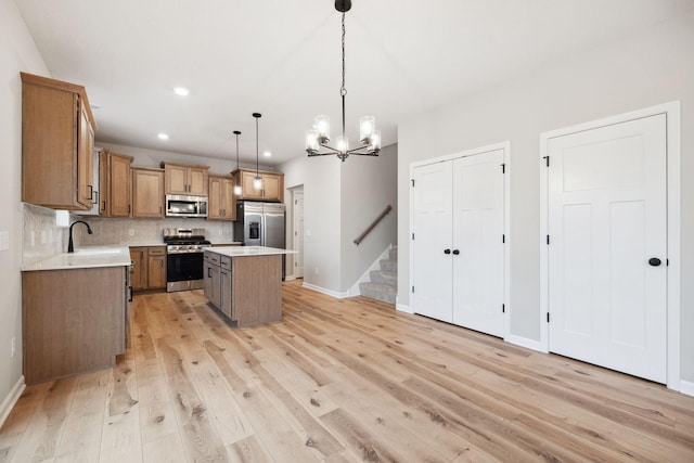 kitchen featuring light hardwood / wood-style flooring, hanging light fixtures, stainless steel appliances, tasteful backsplash, and a kitchen island