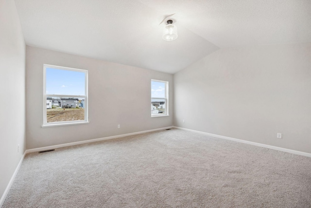 spare room with vaulted ceiling and carpet flooring