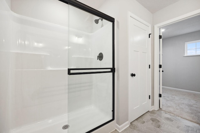 bathroom featuring a shower with shower door and a textured ceiling