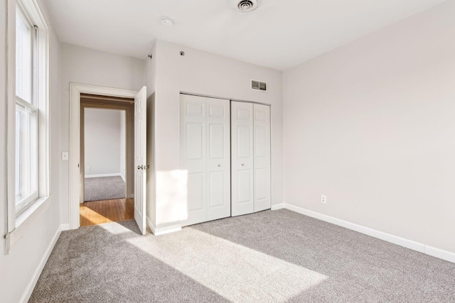 unfurnished bedroom with a closet and light colored carpet