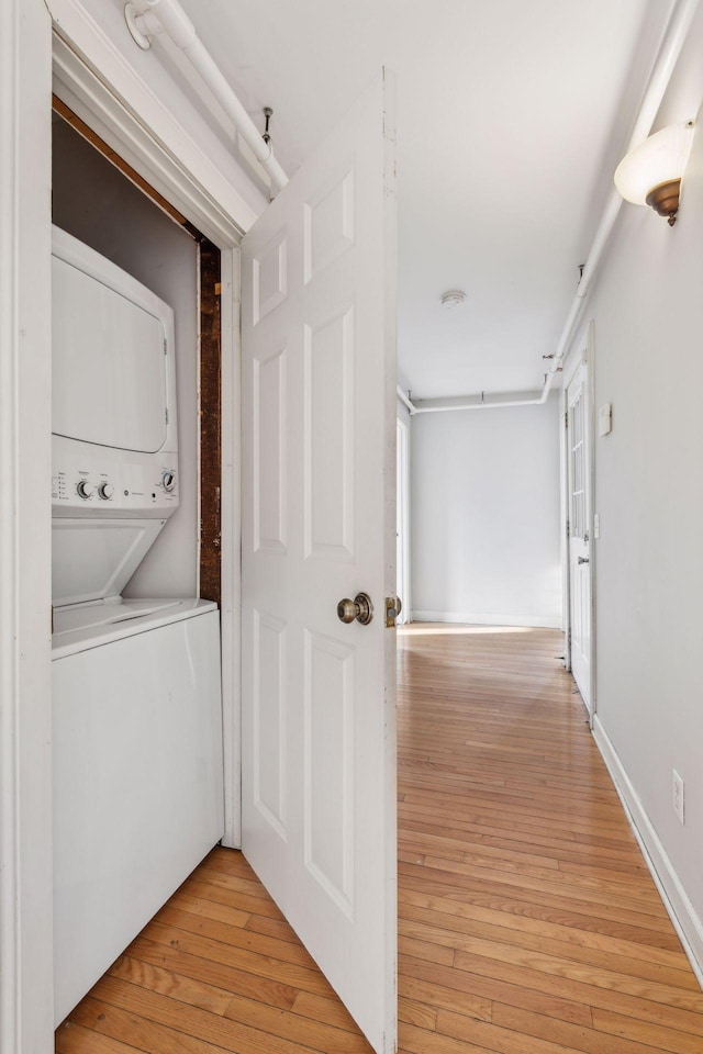 laundry area featuring stacked washer and clothes dryer and light hardwood / wood-style floors