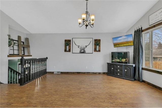 living room featuring hardwood / wood-style flooring, lofted ceiling, and an inviting chandelier