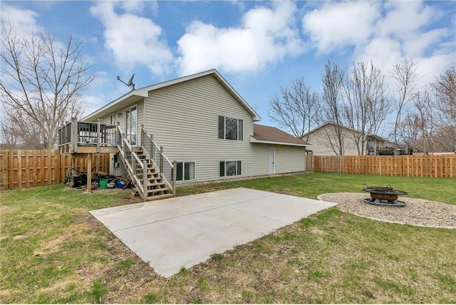 back of house with a wooden deck, an outdoor fire pit, a yard, and a patio