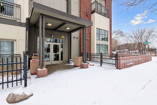 snow covered property entrance featuring french doors