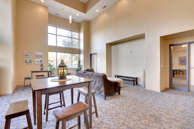 dining space with a high ceiling and light carpet