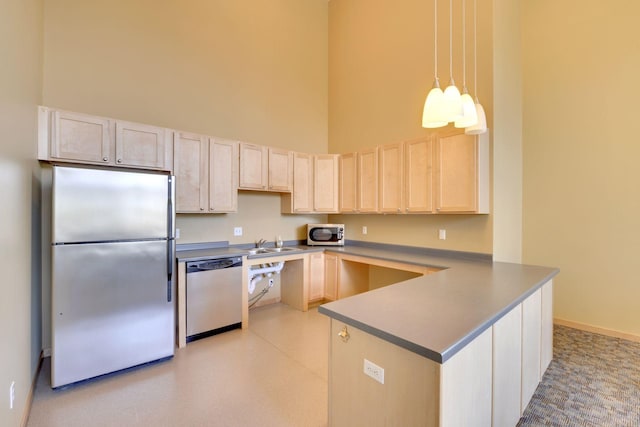 kitchen with sink, appliances with stainless steel finishes, kitchen peninsula, pendant lighting, and a high ceiling