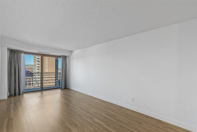 empty room with hardwood / wood-style floors and a textured ceiling